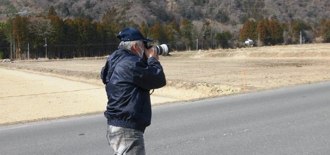 3 帰還困難地区で写真を撮る飛田晋秀氏（研究会案内チラシより） - 「低線量被ばく問題研究会」<br> 第8回研究会